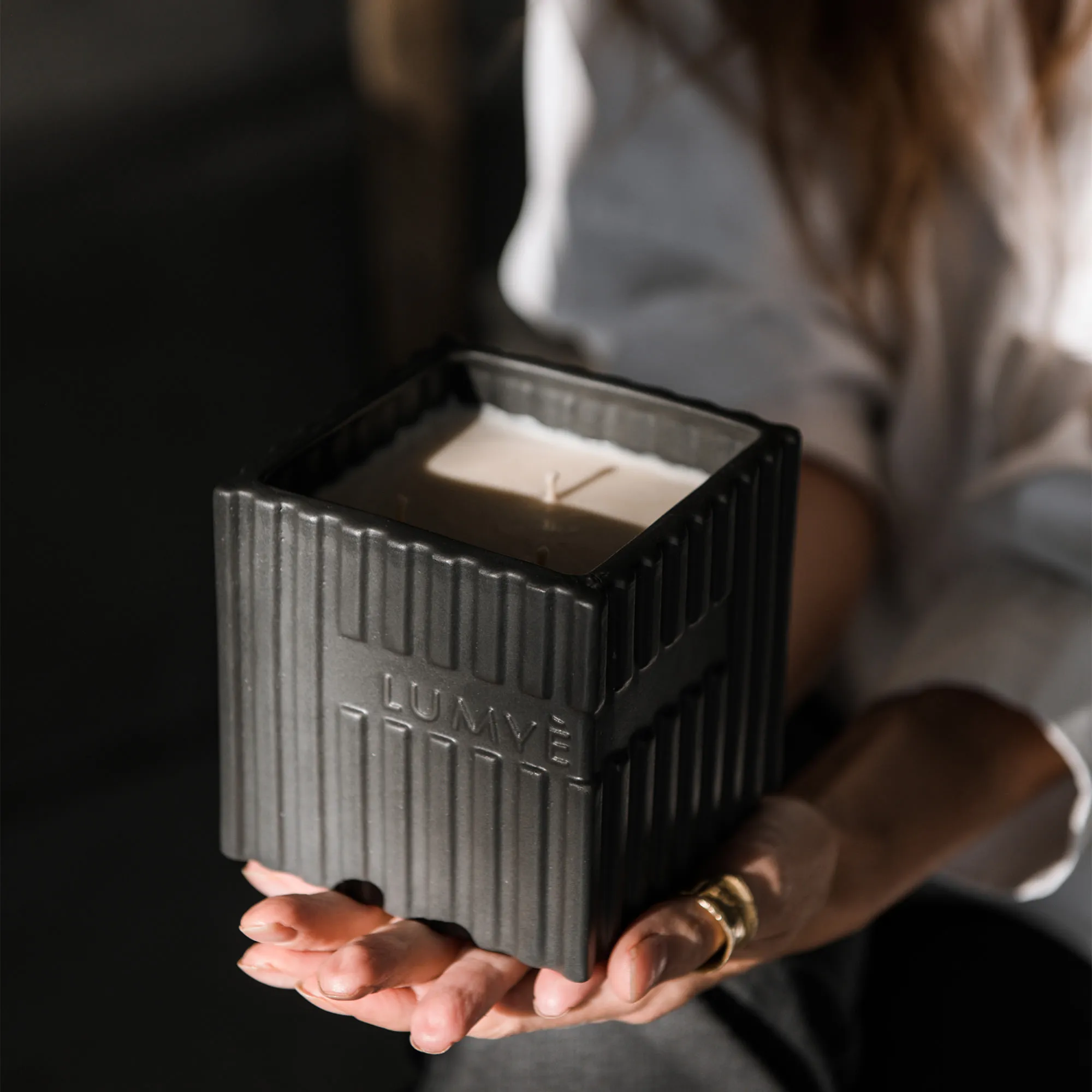 Large LUMYÈ 500 g candle in black designer ceramics held in hands