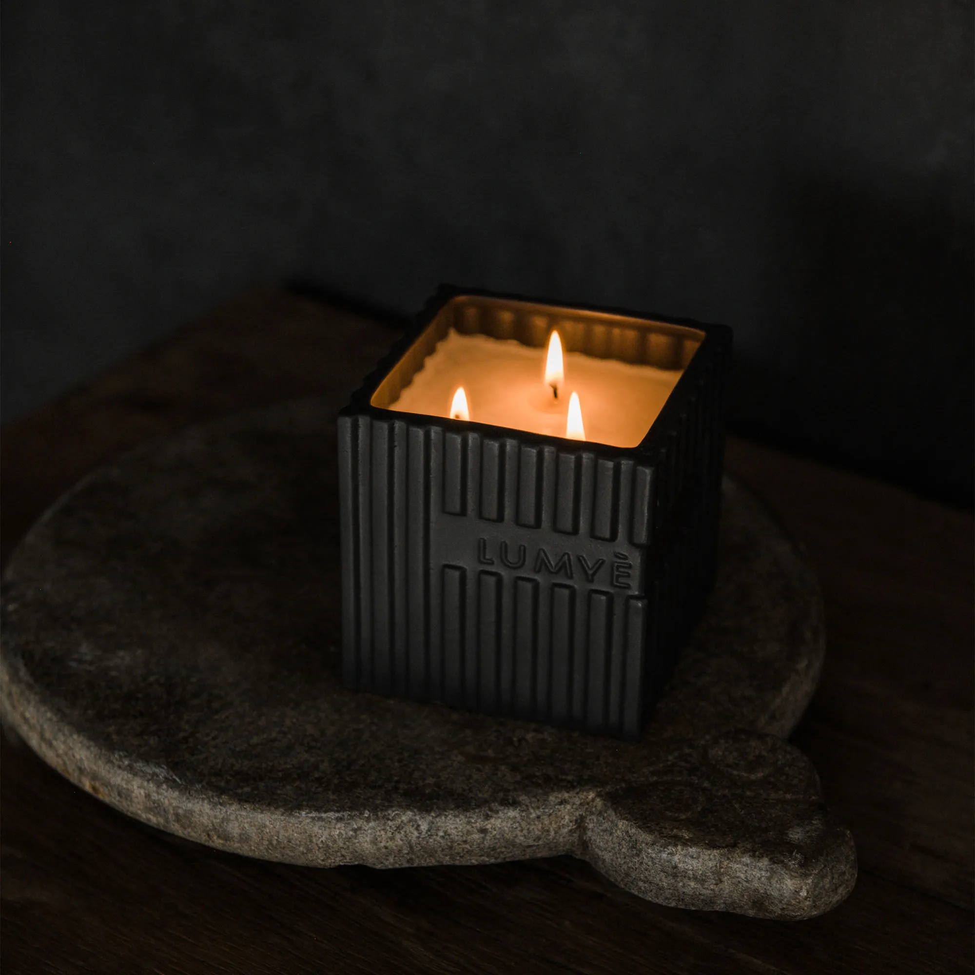 LUMYÈ candle in black ceramics lit on a stone board — a corporate Christmas gift